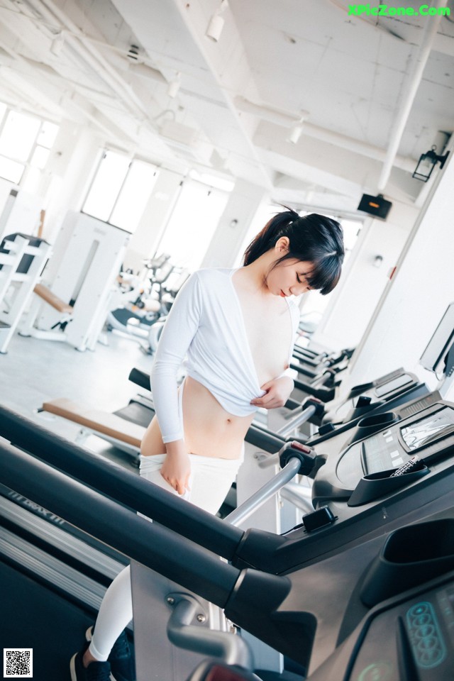 A woman is running on a treadmill in a gym.