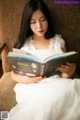 A woman sitting on a couch reading a book.