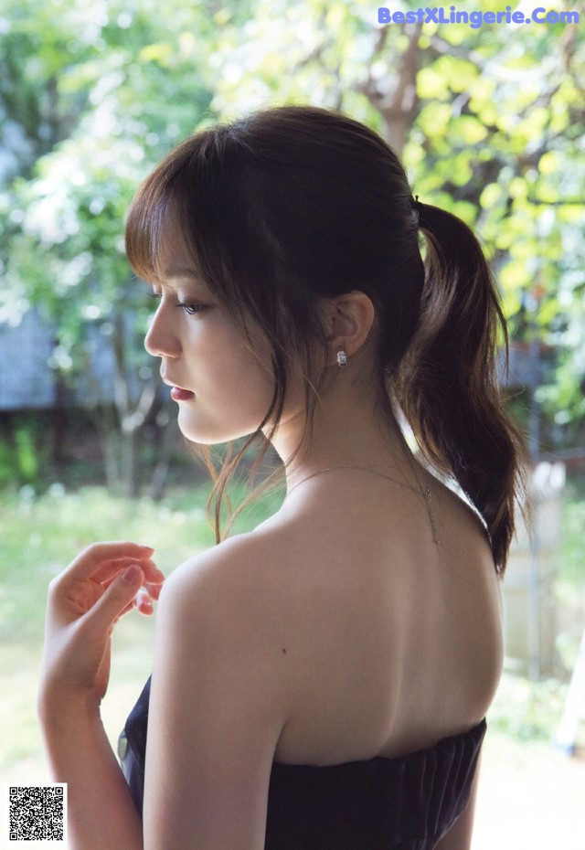 A woman in a black dress looking out a window.