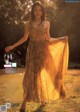 A woman in a long dress standing in a field.