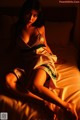 A woman sitting on a bed in a dress.