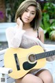 A woman sitting on a bench holding a guitar.