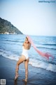 A woman in a white bathing suit standing on the beach.