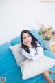 A woman sitting on a blue couch with a white pillow.