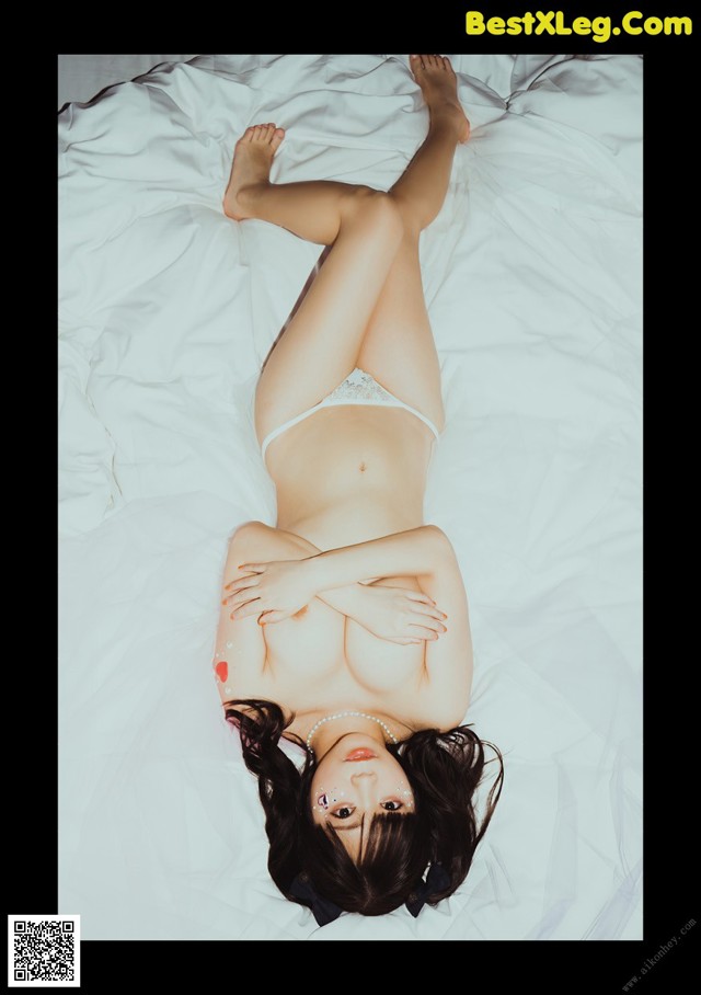 A woman laying on top of a white bed.