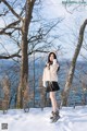 A woman standing in the snow near a body of water.