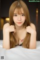 A woman with long brown hair laying on a bed.