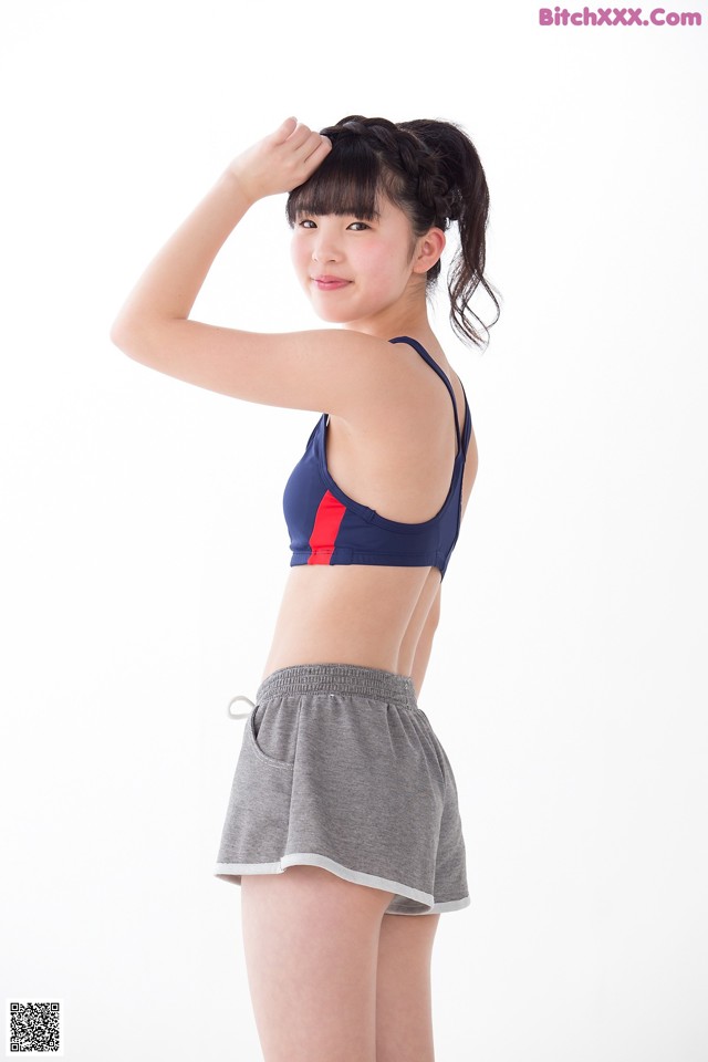 A woman in a blue and red sports bra top and gray shorts.