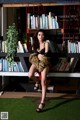 A woman sitting on a chair in front of a bookshelf.