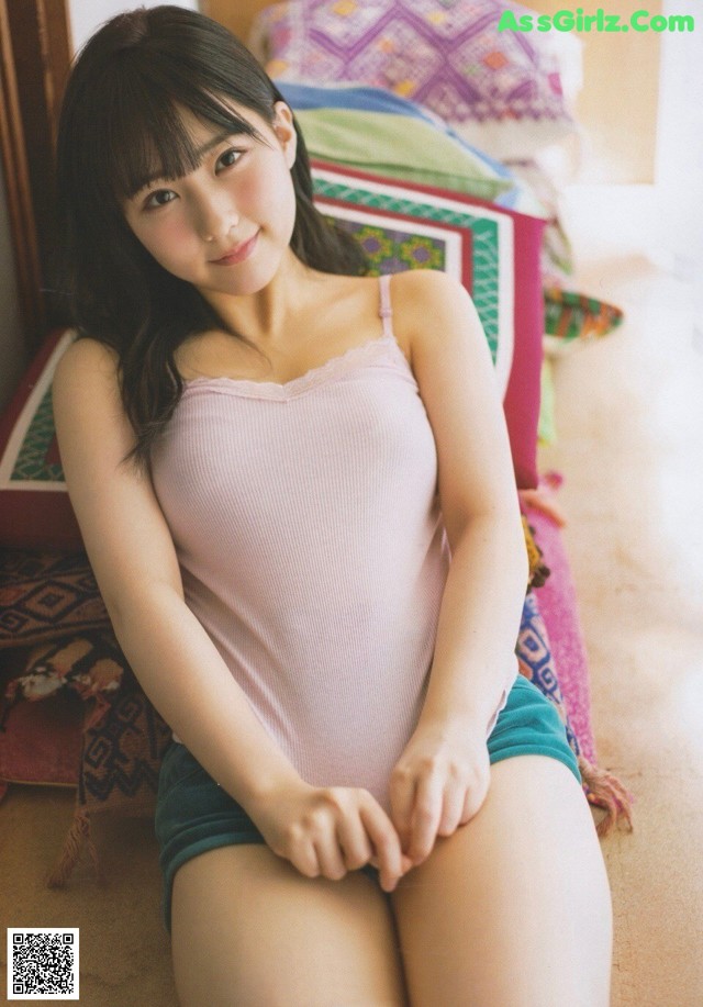 A woman sitting on the floor in a pink tank top.