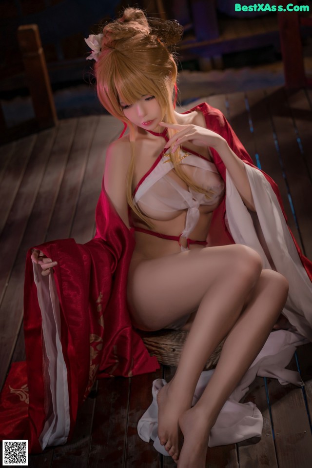 A woman in a red and white outfit sitting on a wooden floor.