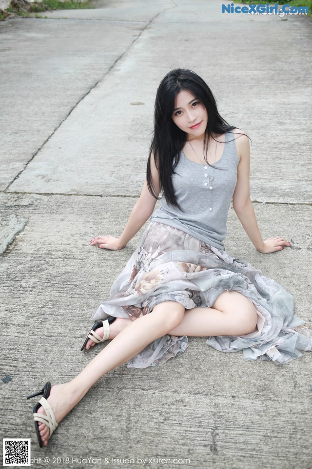 A woman sitting on the ground with her legs crossed.