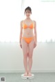 A woman in an orange bikini standing on a scale.